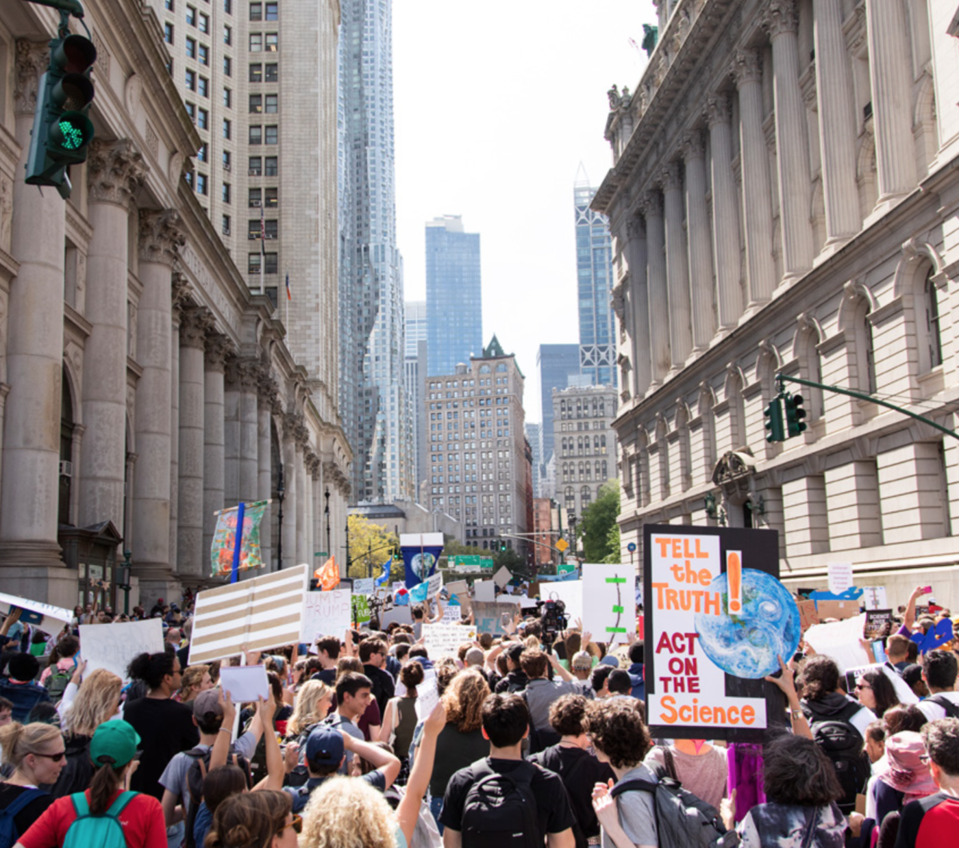 On a New York City street, a crowd of youth hold signs of in support of science and addressing climate change.